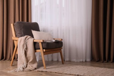 Pencerenin yanında battaniyesi olan rahat bir koltuk, yazı için de yer var. İç tasarım