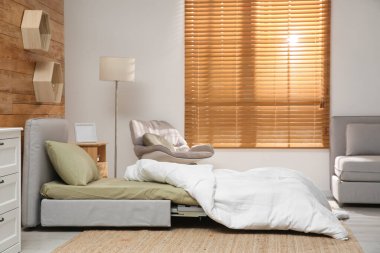 Odanın içinde ahşap duvarın yanında yataklı kanepe var. Misafir için ek yer