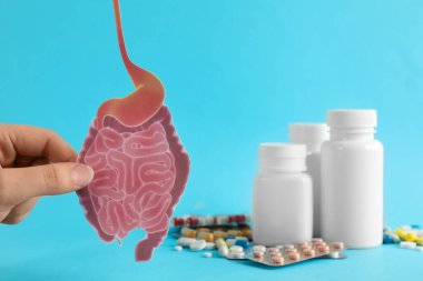 Kadının elinde kağıt bağırsak var. Turkuaz arka planda hapların yanında. Yakın plan.