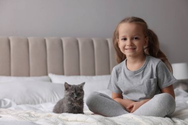 Evde yatağında kedi yavrusu olan sevimli küçük bir kız. Çocukluk hayvanı.