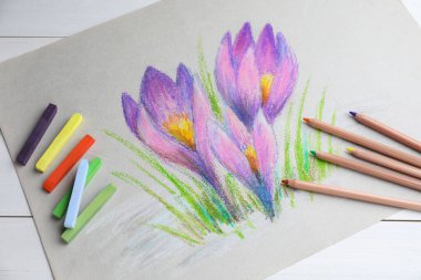 Renkli tebeşirle boyanmış pasteller, kalemler ve beyaz ahşap masa üzerindeki güzel kır çiçekleri tablosu.