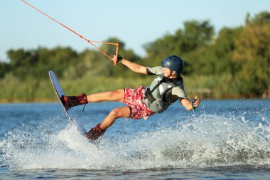 Genç çocuk nehirde wakeboard yapıyor. Aşırı su sporu