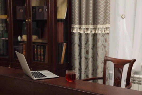読書室の木製テーブルの上のノートパソコンとお茶のカップ — ストック写真