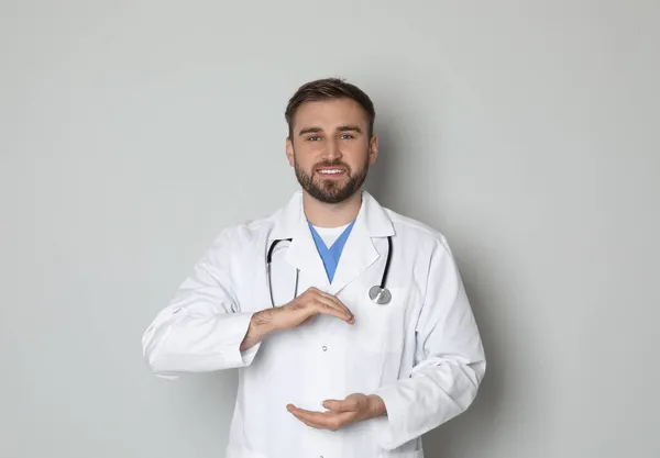 Ung Läkare Håller Något Ljusgrå Bakgrund — Stockfoto