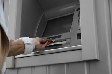 Para çekmek için para makinesini kullanan bir kadın. Açık hava, yakın çekim.