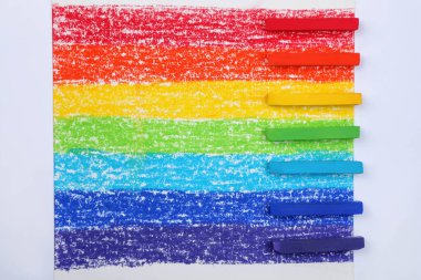 Gökkuşağı resminde renkli pastel tebeşirler, düz uzanmış. Çizim malzemeleri