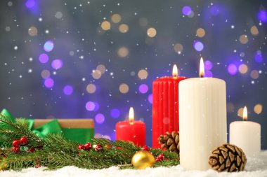 Yanan mumların üzerine kar yağıyor ve bulanık Noel ışıklarına karşı şenlikli bir dekor, metin için yer var.