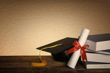 Mezuniyet şapkası, kitaplar ve diploma tahta masada. Metin için boşluk