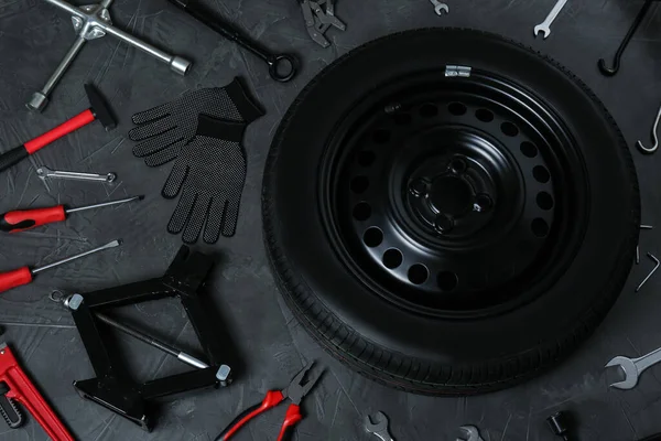 深灰色表面上的汽车轮 剪子千斤顶和各种工具 — 图库照片