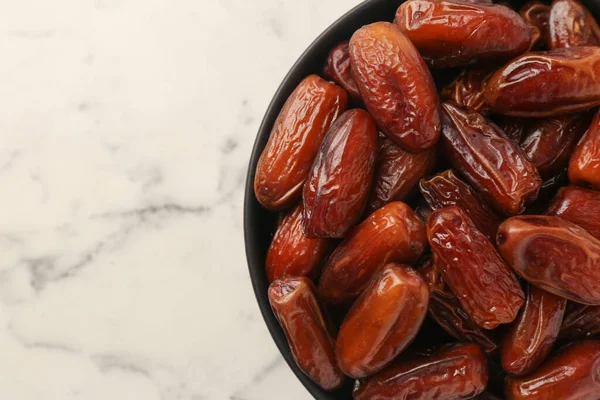 Beyaz mermer masada, kasede kurutulmuş tatlı hurmalar, üst manzara. Metin için boşluk