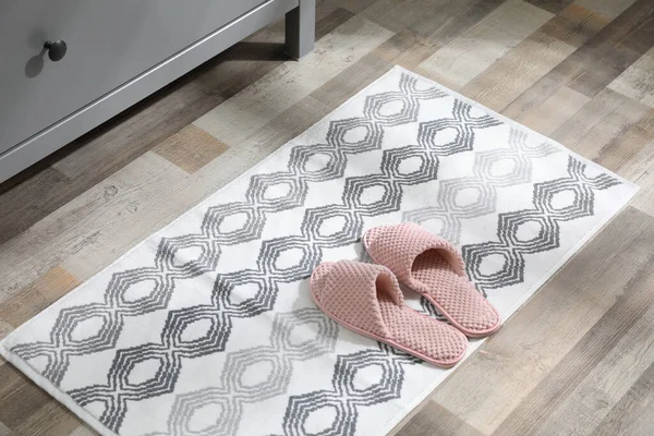 İçerideki gri çekmecelerin yanında terlikleri olan mat.