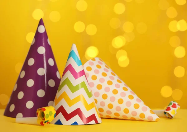 Hermosos Sombreros Fiesta Sopladores Mesa Amarilla Contra Las Luces Borrosas —  Fotos de Stock