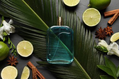 Düz kompozisyon, parfüm şişesi ve taze narenciye ile gri masada duruyordu.