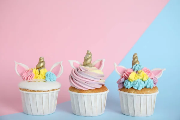 色の背景にかわいいユニコーンのカップケーキ3つ — ストック写真
