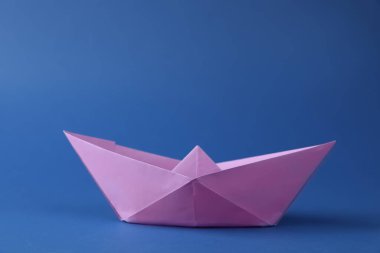 Mavi arka planda el yapımı menekşe kağıt tekne. Origami sanatı