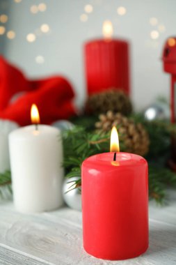Bulanık festival ışıklarına karşı beyaz ahşap masada mum yakmak. Noel arifesi