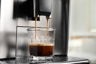 Espresso makinesi bardağa kahve dolduruyor. Arka plan bulanık, yakın plan. Metin için boşluk