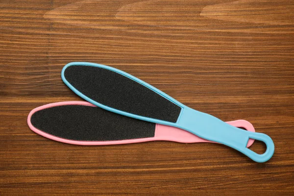 Colorful foot files on wooden table, flat lay. Pedicure tools