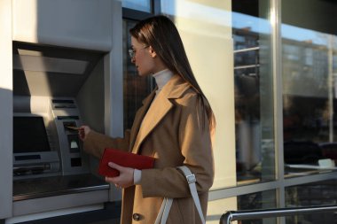 Dışarıda para çekmek için para makinesini kullanan genç bir kadın.