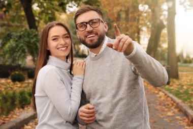 Sonbahar parkında şık kıyafetler giyen mutlu çift.