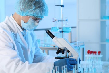 Laboratuvarda mikroskopla çalışan bir bilim adamı. Tıbbi araştırma