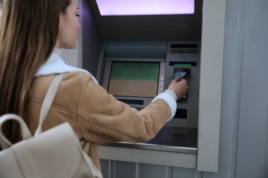 Para çekmek için para makinesini kullanan genç bir kadın.