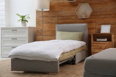 Odanın içinde ahşap duvarın yanında yataklı kanepe var. Misafir için ek yer