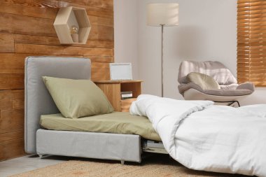 Odanın içinde ahşap duvarın yanında yataklı kanepe var. Misafir için ek yer