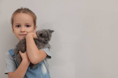 Hafif arka planda kedi yavrusu olan sevimli küçük bir kız, mesaj için yer var. Çocukluk hayvanı.