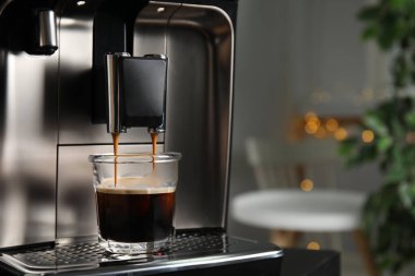 Espresso makinesi bardağa kahve dolduruyor. Arka plan bulanık, yakın plan. Metin için boşluk
