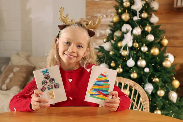 Roztomilé Malé Dítě Krásnými Vánočními Pohlednicemi Stolu Zdobeném Pokoji — Stock fotografie