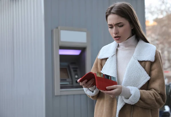 在室外取款机旁拿钱包的不快乐的年轻女人 — 图库照片