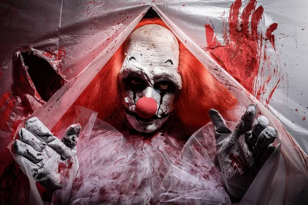 Furchteinflößender Clown Der Durch Ein Loch Zerrissener Blutverschmierter Plastikfolie Starrt — Stockfoto
