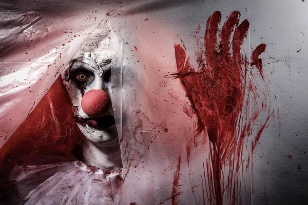 Furchteinflößender Clown Der Durch Ein Loch Zerrissener Blutverschmierter Plastikfolie Starrt — Stockfoto