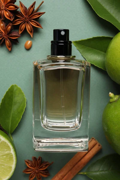 Soluk yeşil arka planda parfüm şişesi ve taze narenciye meyveleriyle bezenmiş düz bir kompozisyon.