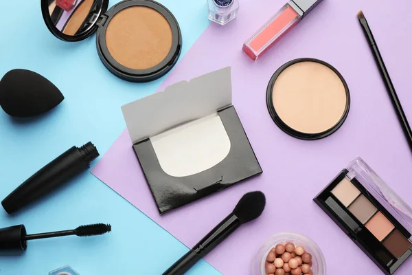 Flat lay composition with facial oil blotting tissues and makeup products on color background. Mattifying wipes