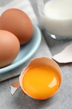 Çiğ tavuk yumurtası ve yumurta sarısı açık gri masada, yakın plan.