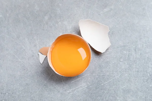 Gebarsten Eierschaal Met Rauwe Dooier Lichtgrijze Tafel Bovenaanzicht — Stockfoto