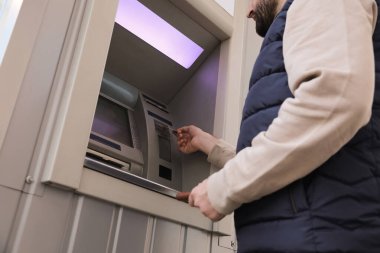 Dışarıdaki ATM 'ye kredi kartı takan adam, düşük açılı.