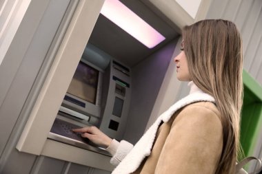 Bankamatiğe giriş şifresi açık havada genç bir kadın.