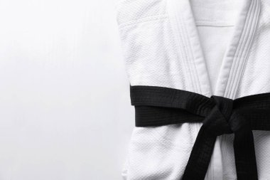 Beyaz ahşap arka planda siyah kuşaklı dövüş sanatları üniforması. Metin için boşluk