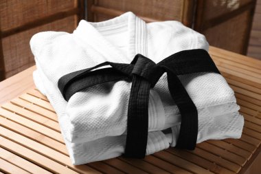 Martial arts uniform with black belt on table indoors clipart