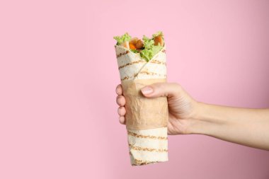 Pembe arka planda nefis tavuk yahnisi tutan kadın, yakın plan.