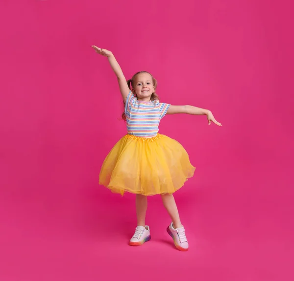 분홍색 배경으로 춤추는 스커트입은 귀여운 — 스톡 사진