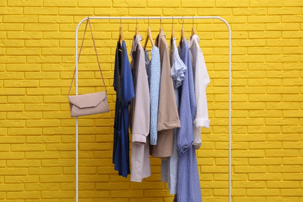 Rack Met Verschillende Stijlvolle Kleding Tas Buurt Van Gele Bakstenen — Stockfoto