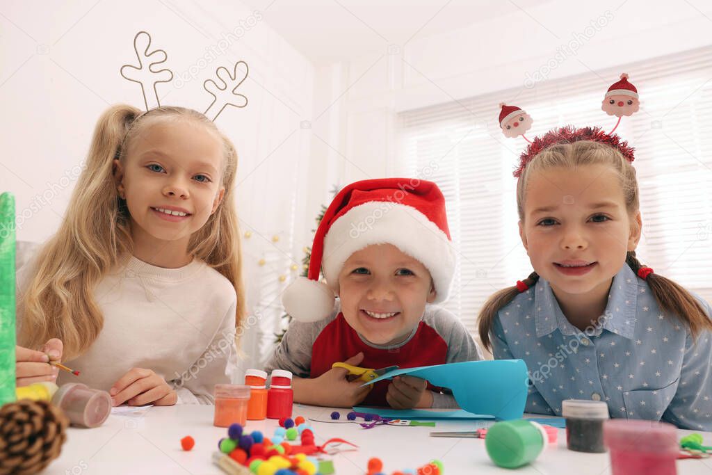 Cute little children making Christmas crafts at table in room