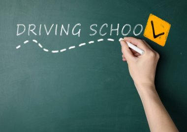 Sürücü okulu konsepti. Yeşil tahtanın yanında beyaz tebeşirli kadın, yakın plan.