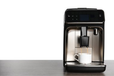 Modern espresso makinesi beyaz arka plana karşı tahta masaya kahve döküyor. Metin için boşluk