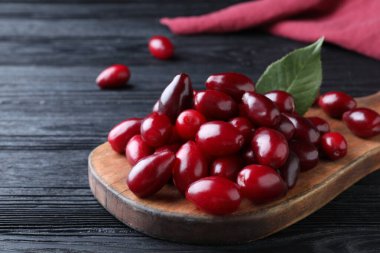 Siyah ahşap masada yeşil yapraklı taze kızılcık üzümleri, yakın plan.