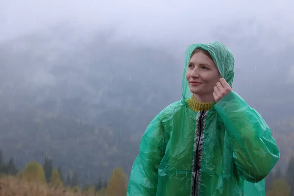 雨の下で山の景色を楽しむレインコートの若い女性 — ストック写真